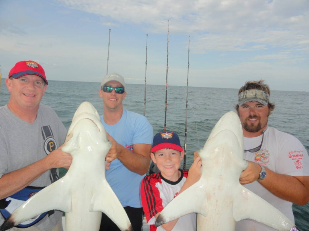 Shark Fishing Charters In Myrtle Beach. Men and kid holden two sharks. Shark Fishing Charters In Myrtle Beach near me.
Men and kid holden two sharks.