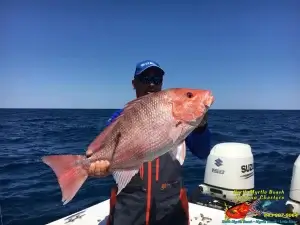 image captain keith logan holding a red snapper on a deep sea fishing charter out north myrtle beach